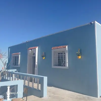a blue house with a blue wall and a staircase at Maison d'Azur in Sidi Abdalwahad
