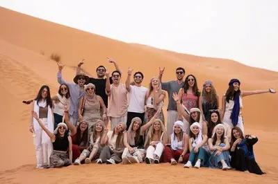 a group of people posing in the desert at Merzouga Erg Luxury Camp in Merzouga