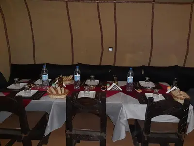 a table with chairs and bottles of water on it at Merzouga Erg Luxury Camp in Merzouga