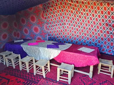 a bedroom with a bed and stools in it at Hami desert camping in Merzouga