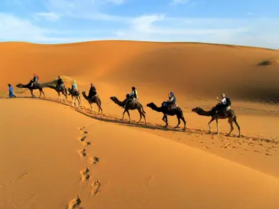 a group of people riding horses in the desert at Merzouga campsite in Merzouga
