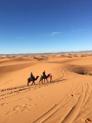 two people riding horses in the desert at Merzouga campsite in Merzouga