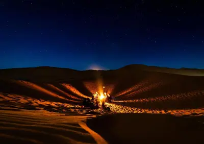 a desert at night with a starry sky at Merzouga campsite in Merzouga