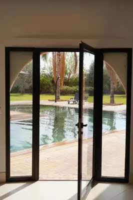 an open glass door with a view of a pool at Villa Michel Lucas in Marrakech