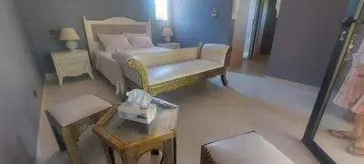 a bedroom with a bed and a chair and a table at Villa Michel Lucas in Marrakech