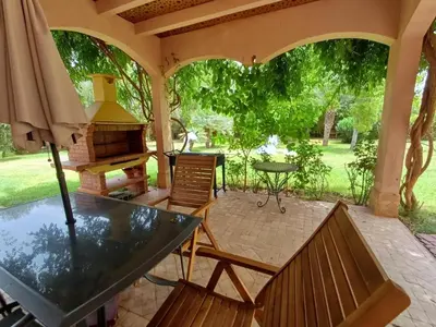 a patio with a table and chairs and a grill at Villa Michel Lucas in Marrakech