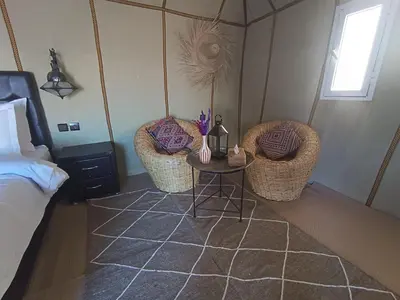 a bedroom with two chairs and a table and a bed at Erg Chebbi Luxury Package & Activities in Merzouga