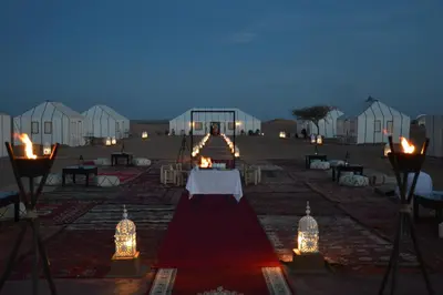 a room with a table with lights and white tents at Erg Chebbi Luxury Package & Activities in Merzouga