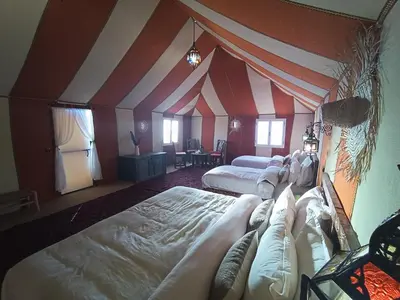 a room with two beds and a striped ceiling at Erg Chebbi Luxury Package & Activities in Merzouga
