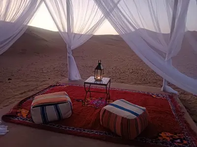 a room with two beds and a table in the desert at Erg Chebbi Luxury Package & Activities in Merzouga