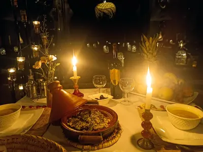 a table with two candles and a plate of food at Erg Chebbi Luxury Package & Activities in Merzouga