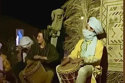a group of people standing around a woman sitting on a drum at Erg Chebbi Luxury Package & Activities in Merzouga