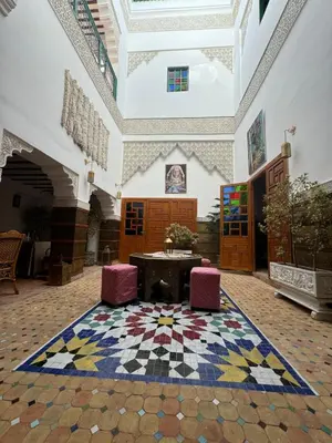 a room with a table and two chairs and a rug at Riad Sidi in Fès