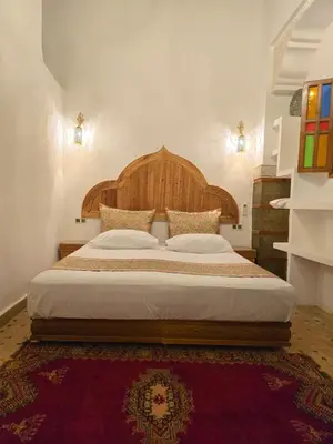 a bedroom with a large bed with a wooden headboard at Riad Sidi in Fès