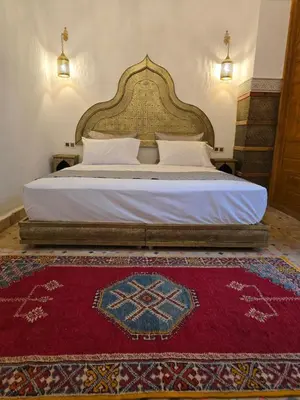 a bedroom with a large bed with a red rug at Riad Sidi in Fès