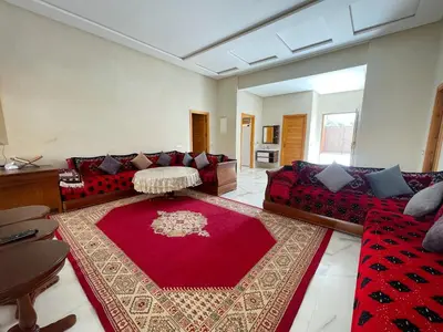 a living room with red couches and a red rug at Villa Ghaith in Douar Tounsi