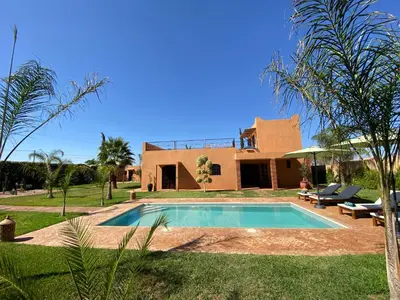 a villa with a swimming pool in front of a house at Dar Mazaheer in Ouanina