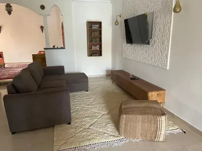 a living room with a couch and a tv on a wall at Dar Mazaheer in Ouanina