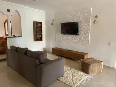 a living room with a couch and a tv on a wall at Dar Mazaheer in Ouanina