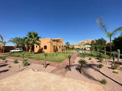 a building with palm trees in front of a yard at Dar Mazaheer in Ouanina