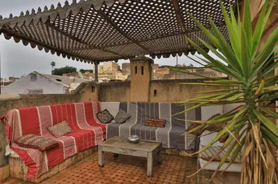 a couch sitting under an umbrella on a patio at Fez Valley Luxury Camp in Fès