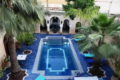 a swimming pool in a courtyard with palm trees at Chambres Émeraude et Rubis - Riad Lotus Bleu in Fès
