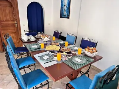 a table with food on it with blue chairs at Chambres Émeraude et Rubis - Riad Lotus Bleu in Fès