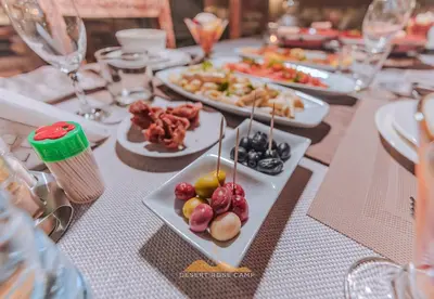 a table topped with plates of food on sticks at Desert Rose Camp in Merzouga