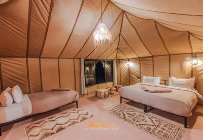 a tent bedroom with two beds and a chandelier at Desert Rose Camp in Merzouga