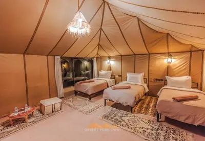 a room with three beds in a tent at Desert Rose Camp in Merzouga