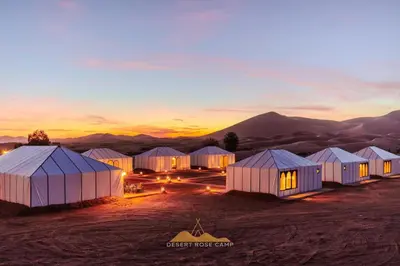 a group of tents in the desert at sunset at Desert Rose Camp in Merzouga