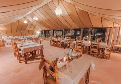 a dining room in a tent with tables and chairs at Desert Rose Camp in Merzouga