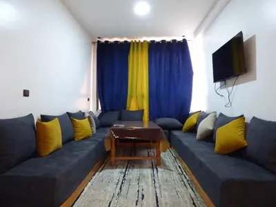a living room with a blue couch with yellow pillows at Diyafat Ghandi in Khenifra
