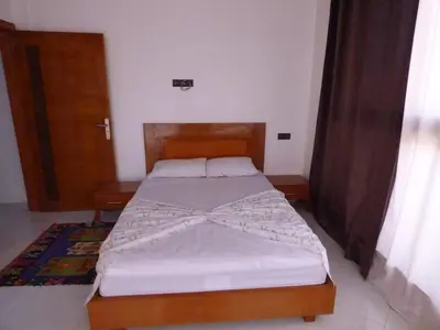 a bedroom with a bed with a wooden headboard at Diyafat Ghandi in Khenifra