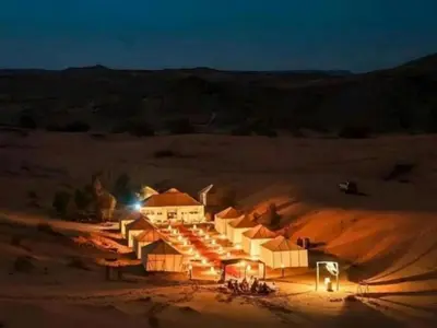 a group of tents in the desert at night at discover luxury camp in Merzouga