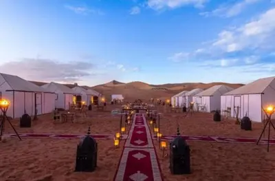 a group of tents in the desert at night at discover luxury camp in Merzouga