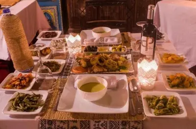 a table with plates of food and a bottle of wine at discover luxury camp in Merzouga