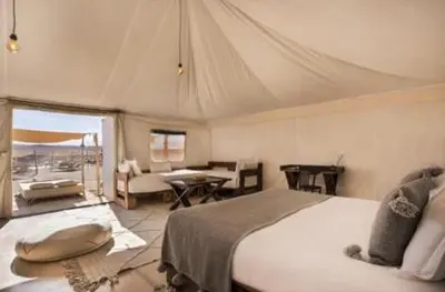 a bedroom with a large bed and a living room at Lunaluxurycamp in Merzouga