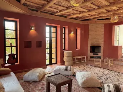 a living room with red walls and white pillows at Lunaluxurycamp in Merzouga