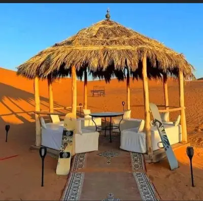 a hut with a table and chairs in the desert at Lunaluxurycamp in Merzouga