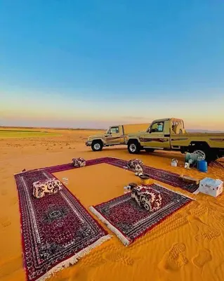 a truck parked in the desert with two carpets at Lunaluxurycamp in Merzouga
