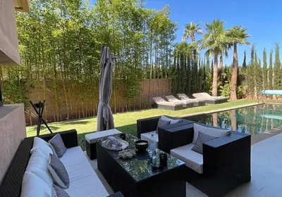 a patio with a couch and a table and an umbrella at Villa youssef in Oulad Tayeb