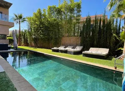 a swimming pool with chaise lounges next to a building at Villa youssef in Oulad Tayeb