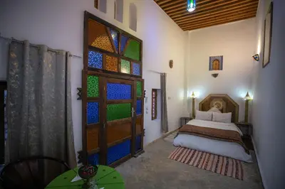 a bedroom with a bed and a door with stained glass at Dar Nana fes in Fès