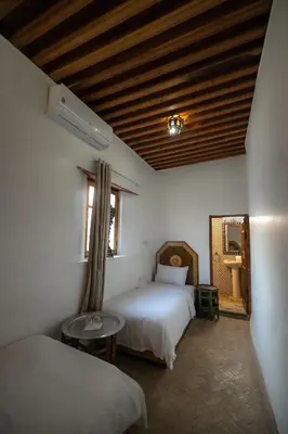 a bedroom with two beds and a table and a window at Dar Nana fes in Fès