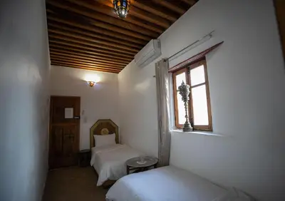 a bedroom with two beds and a window in it at Dar Nana fes in Fès
