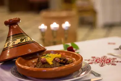 a brown bowl of food on a table with candles at Riad Tahra & Spa in Fès