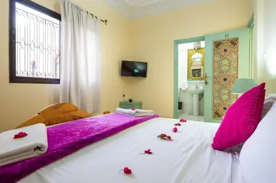 a bedroom with a large bed with pink flowers on it at Riad Qodwa in Fourou