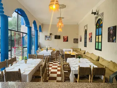 a restaurant with tables and chairs and a couch at Riad Qodwa in Fourou