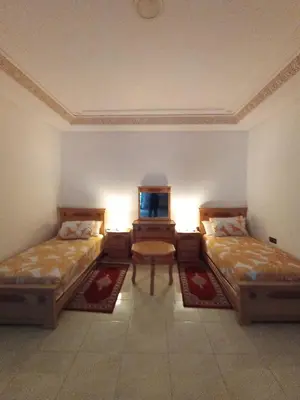 a room with two beds and a table in it at résidence sara in Fès